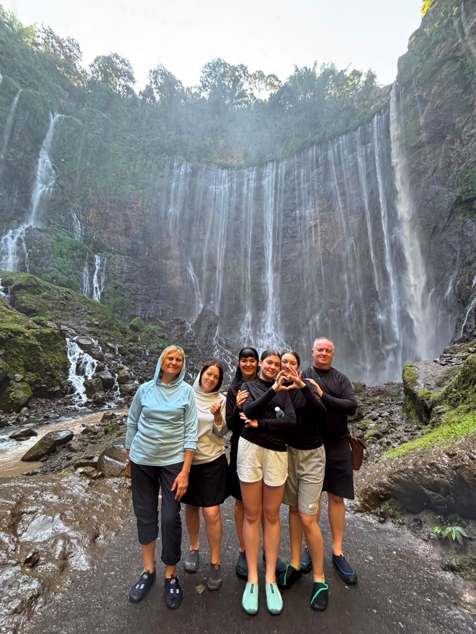 Family of six at the bottom of tumpak sewu waterfall on a private car tour from surabaya
