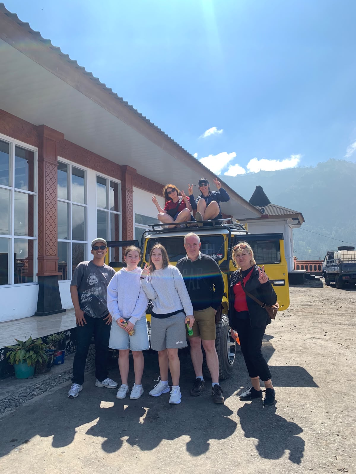 Family posing with a yellow 4x4 jeep on a mount bromo tour from surabaya