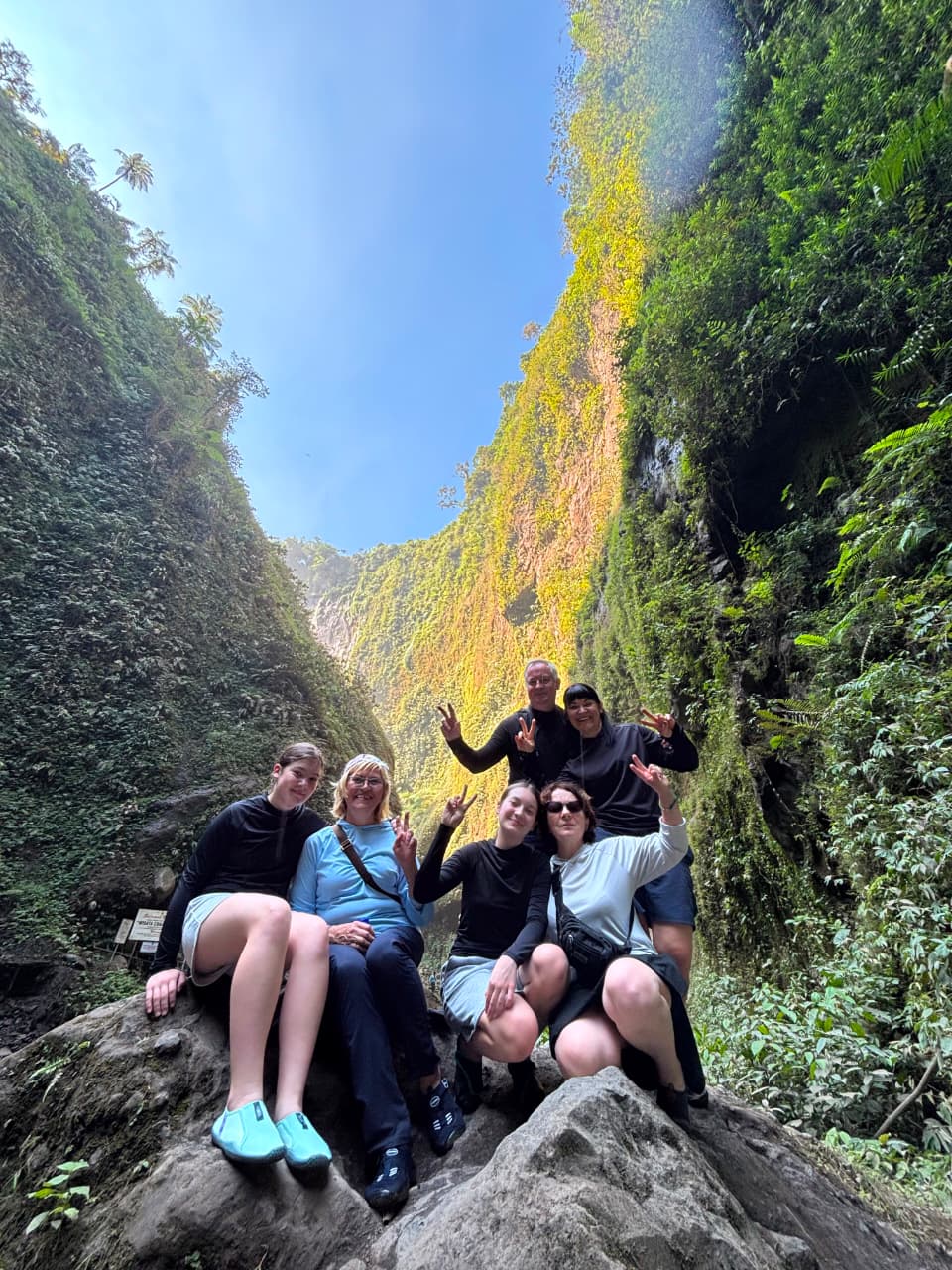 Travelers posing on a boulder deep inside the tumpak sewu gorge, east java